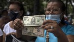 Người phụ nữ cầm tờ đô la Mỹ trong cuộc biểu tình đòi tăng lương ở Caracas, Venezuela ngày 6/9/2022. Ảnh: AP