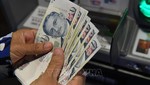 Kiểm đồng đôla Singapore (SGD) tại một máy rút tiền tự động ở Singapore. Ảnh: AFP/TTXVN